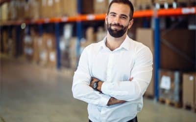 Smiling logistics manager in a warehouse, showcasing expertise in supply chain management and side hustle opportunities.