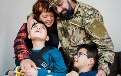 Family embracing, with a veteran in military attire and two children, highlighting support and connection in a home setting, relevant to career transition assistance for families.