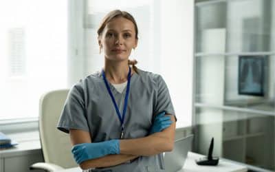 Nurse in scrubs and gloves standing confidently in a modern office setting, representing self-employment success in the healthcare sector.